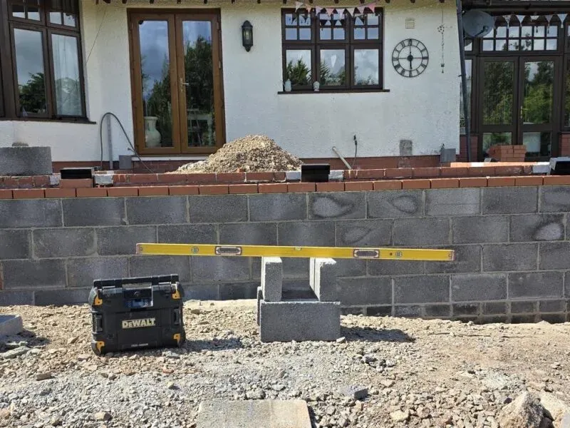 A course of blockwork being laid, a white house behind A course of blockwork being laid, a white house behind
