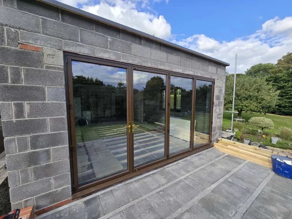 A blockwork extension with brown bifold doors and a patio A blockwork extension with brown bifold doors and a patio