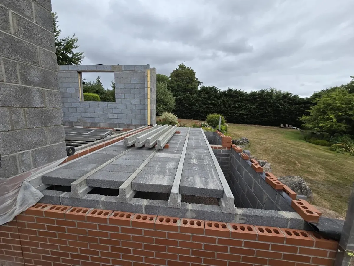 Precast concrete beams spanning new blockwork, with infill blocks going in to form the floor