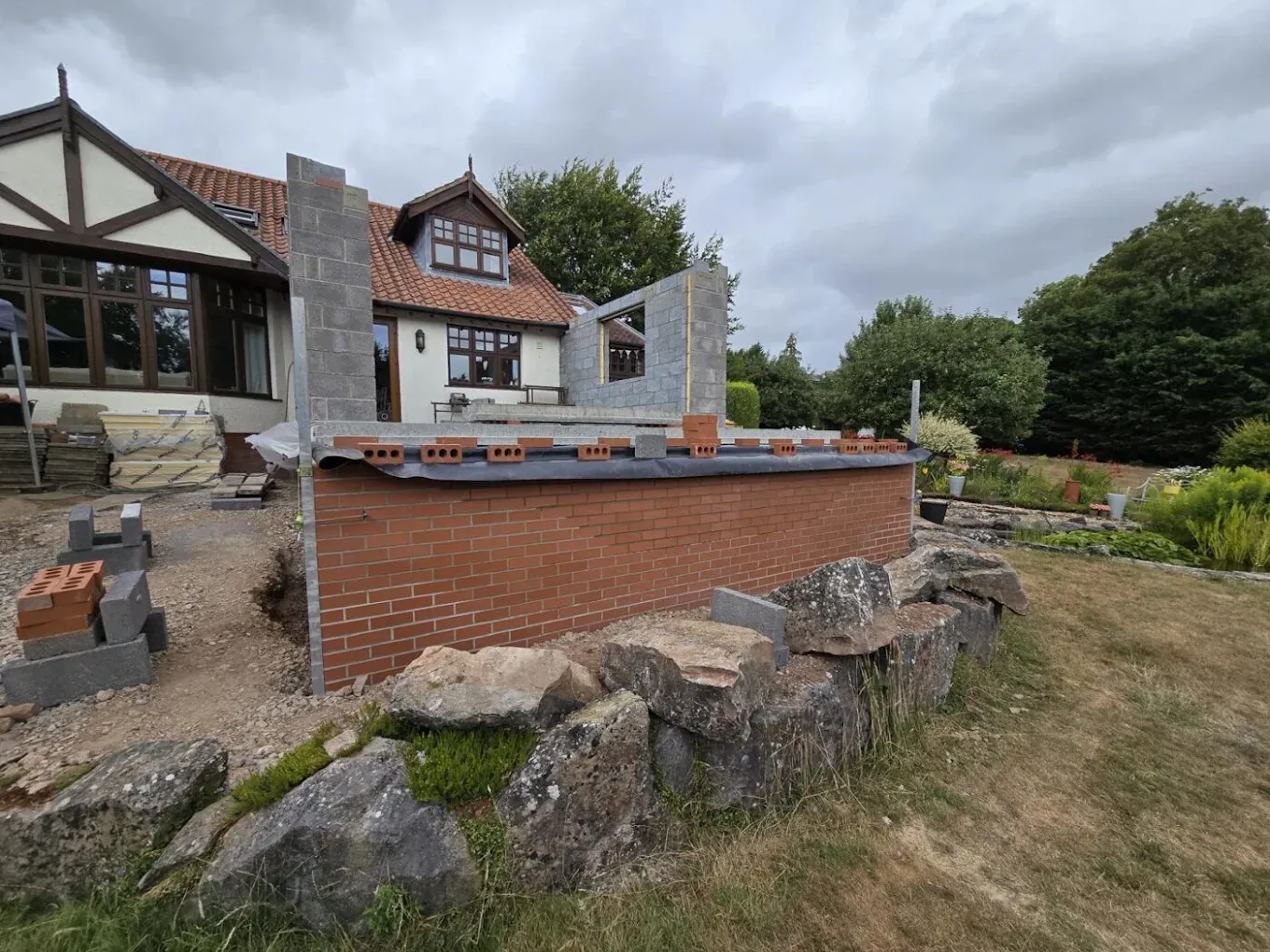 A mock-Tudor house with a brick wall under construction and a rockery A mock-Tudor house with a brick wall under construction and a rockery