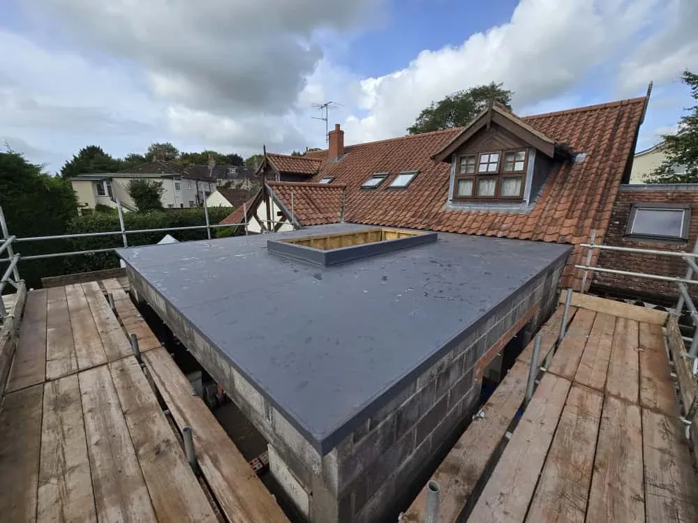A flat roof with a lantern kerb built up, tiled roof behind A flat roof with a lantern kerb built up, tiled roof behind