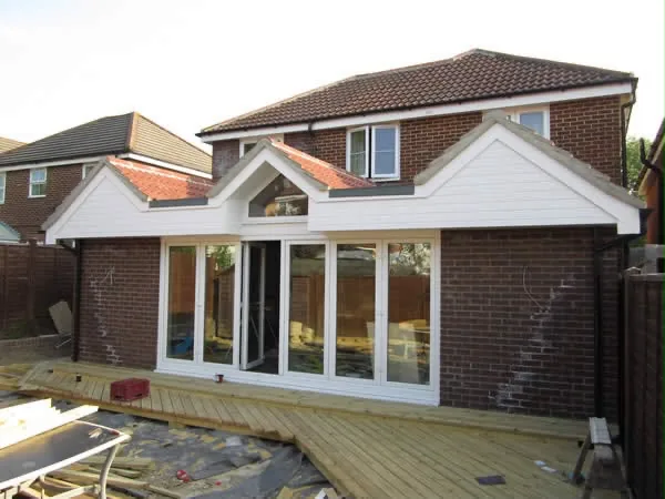 The finished rear elevation in brick and white cladding, with twin gables and new decking The finished rear elevation in brick and white cladding, with twin gables and new decking
