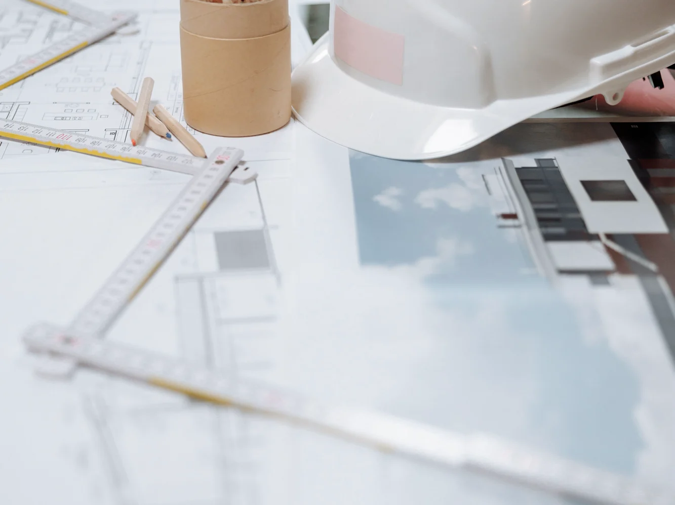 Drawings, a scale rule and a hard hat laid out on a design table