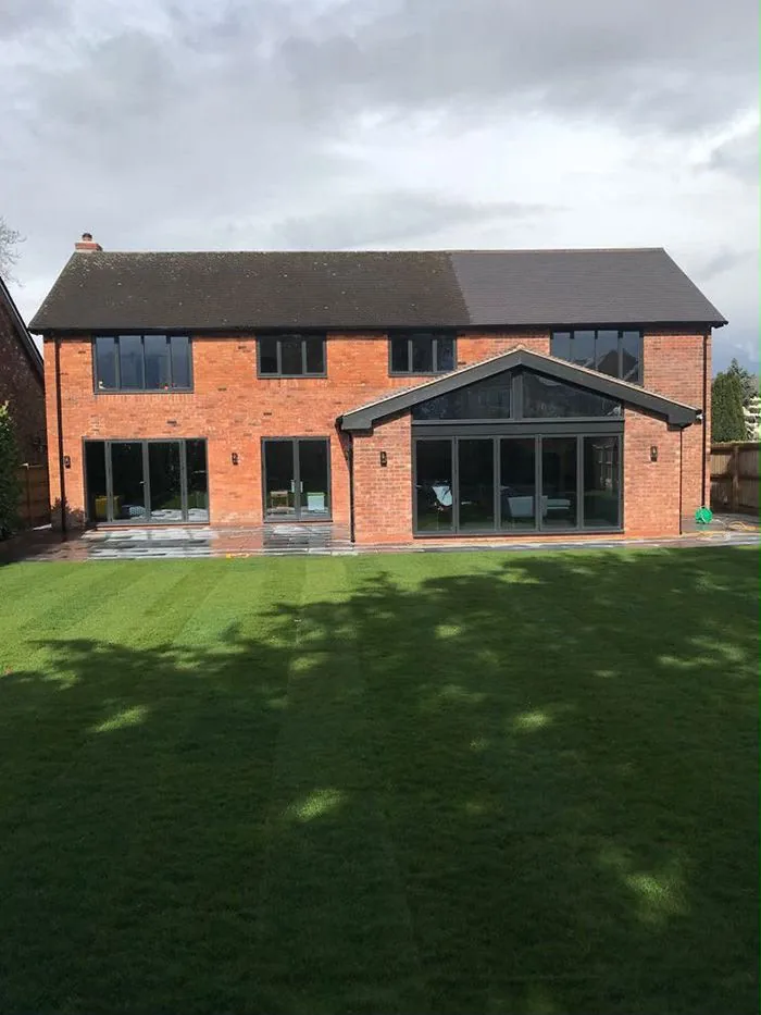 The finished rear elevation in red brick with a glazed gable extension and grey aluminium glazing The finished rear elevation in red brick with a glazed gable extension and grey aluminium glazing