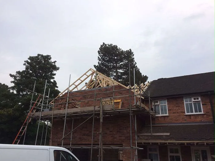 New roof trusses going on over a two-storey brick extension in Weybridge New roof trusses going on over a two-storey brick extension in Weybridge