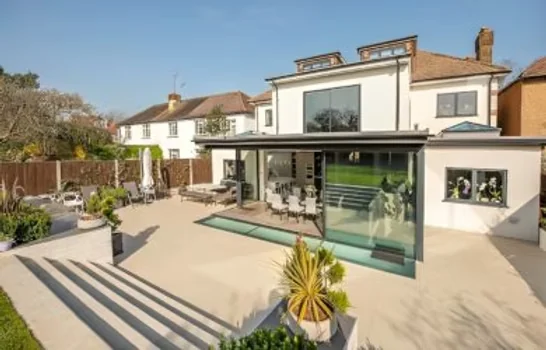 The finished rear of the house with a glazed extension, sliding doors and a wide paved terrace The finished rear of the house with a glazed extension, sliding doors and a wide paved terrace
